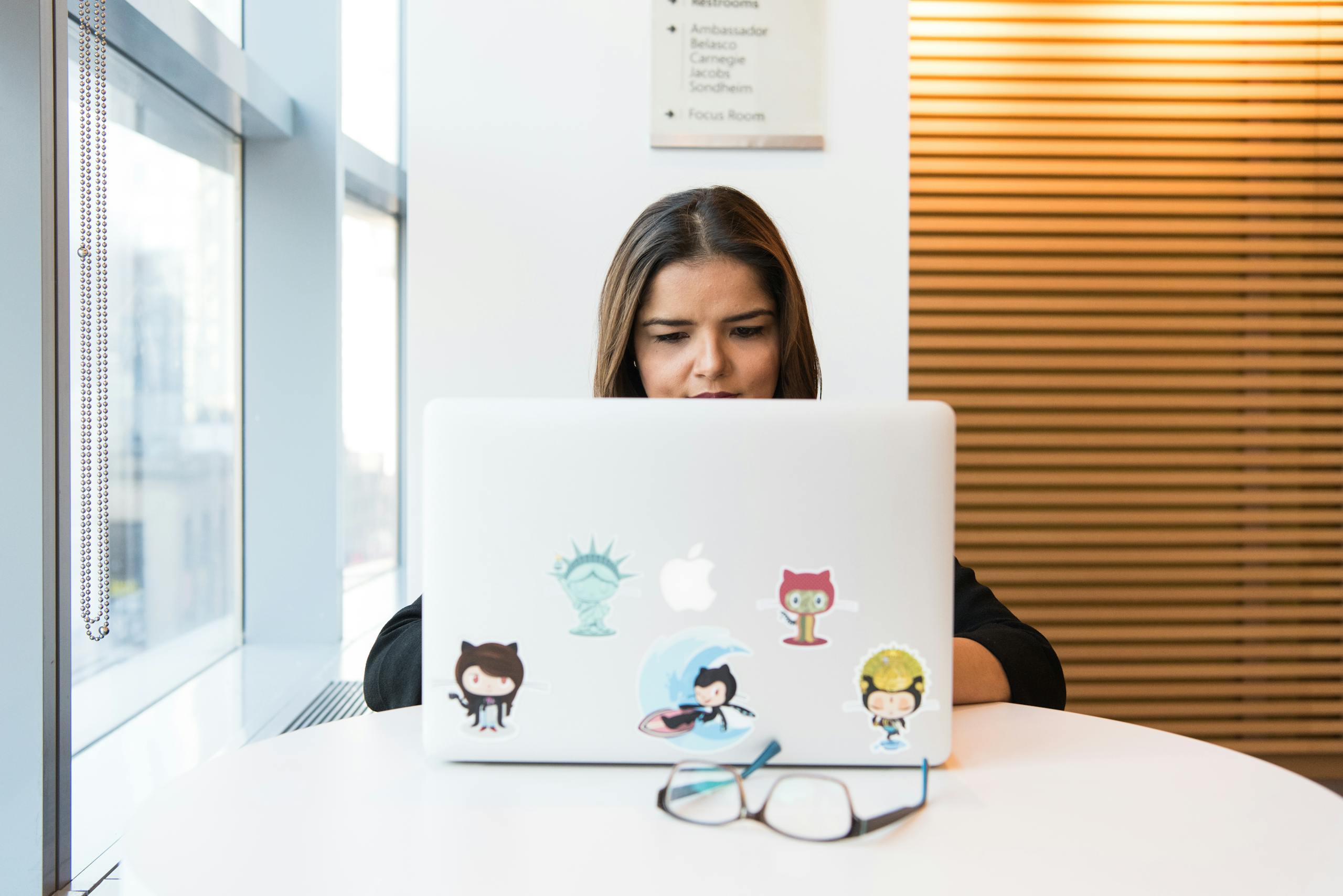 Woman in focus working on software development remotely on laptop indoors.